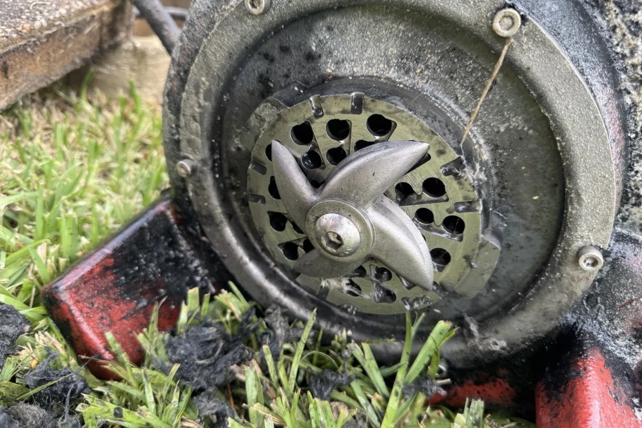 A grinder pump cutter head pulled out and lying on the grass, fouled with debris